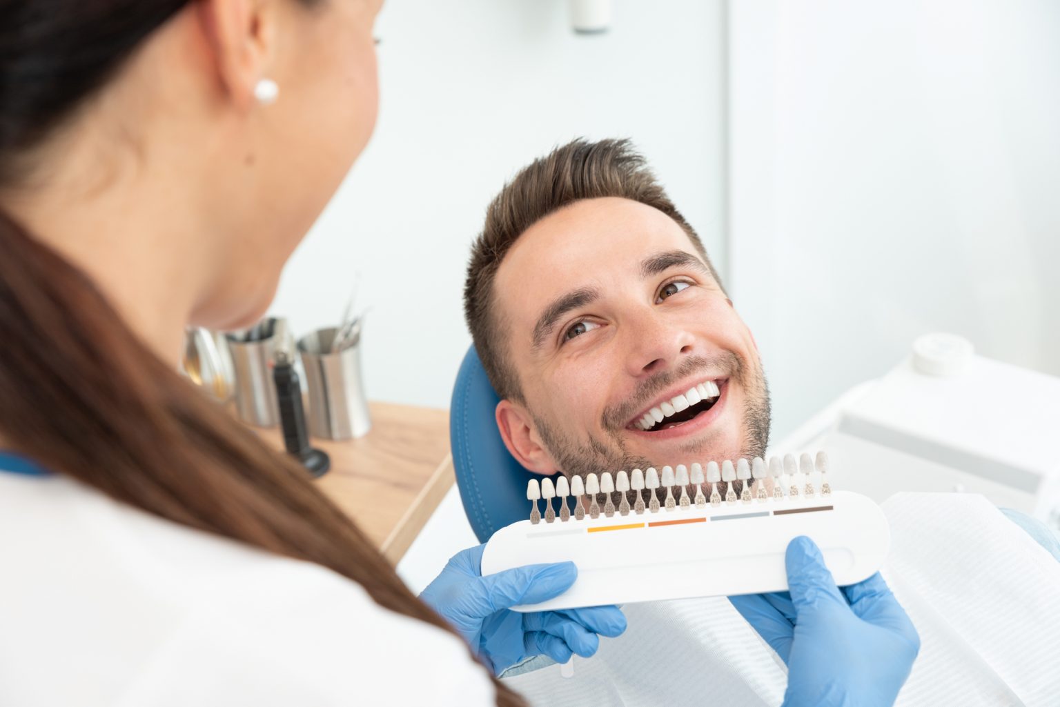 Handsome young man in stomatology clinic with female dentist. Healthy teeth whitening.