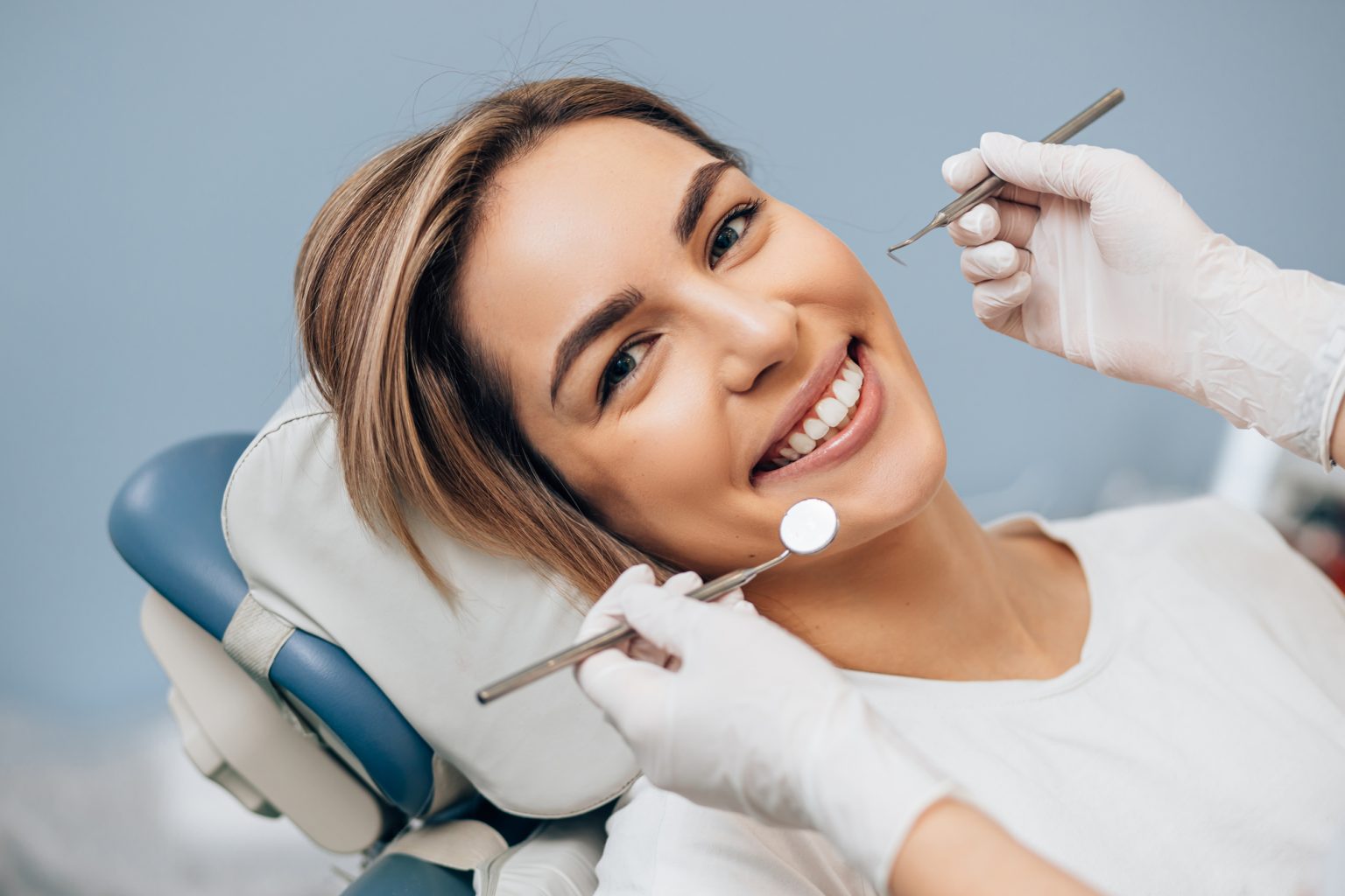 portrait of young caucasian woman with perfect smile in dental office, come to treat spoiled teeth, look at camera